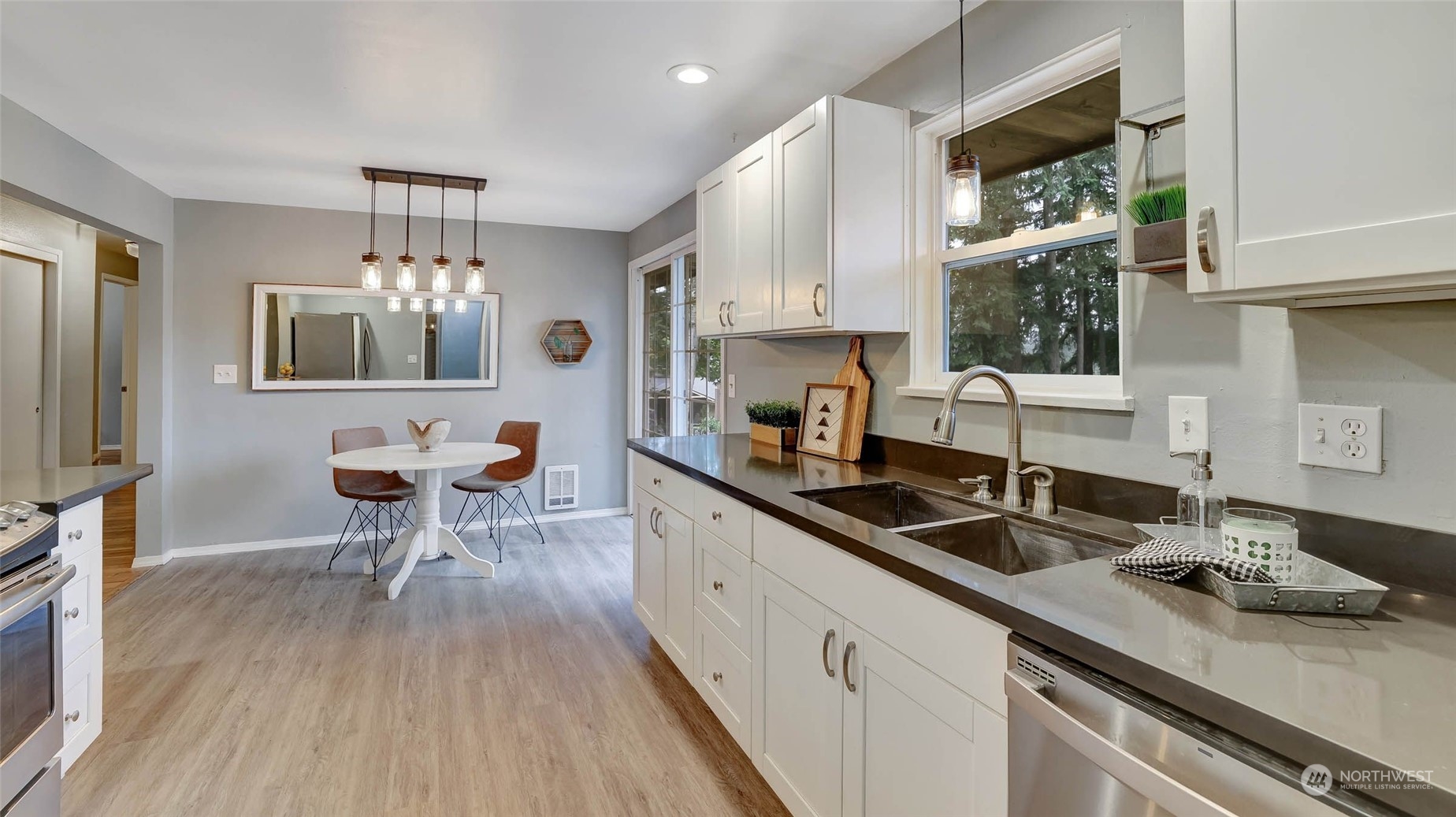 14333 165th Place Southeast Renton, WA 98059 - Photo 11 of 36 a kitchen with a sink dishwasher a stove a dining table and chairs with wooden floor