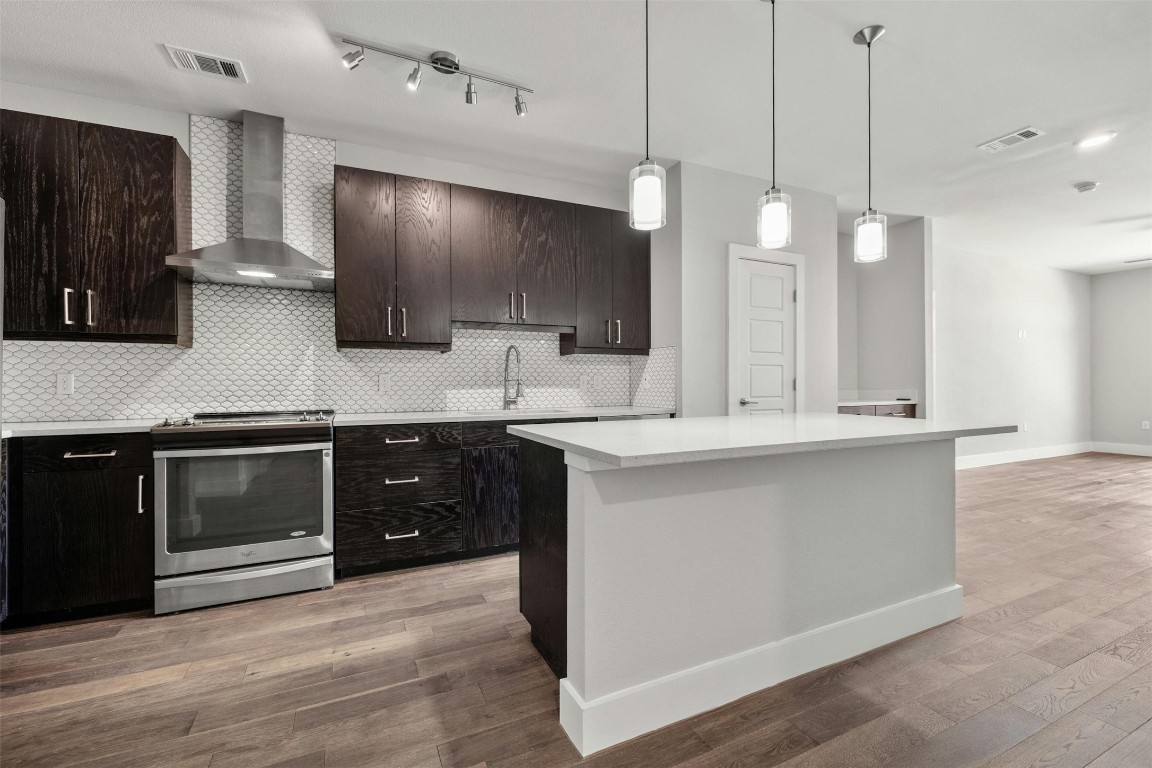 a large kitchen with a large counter top space a sink stainless steel appliances and cabinets