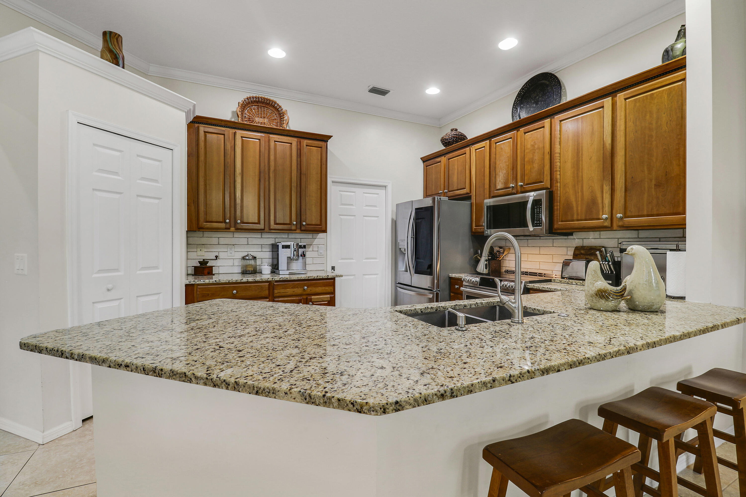 149 Southeast Ashley Oaks Way Stuart, FL 34997 - Photo 21 of 47 a kitchen with granite countertop kitchen island stainless steel appliances a sink a stove a microwave a sink and cabinets