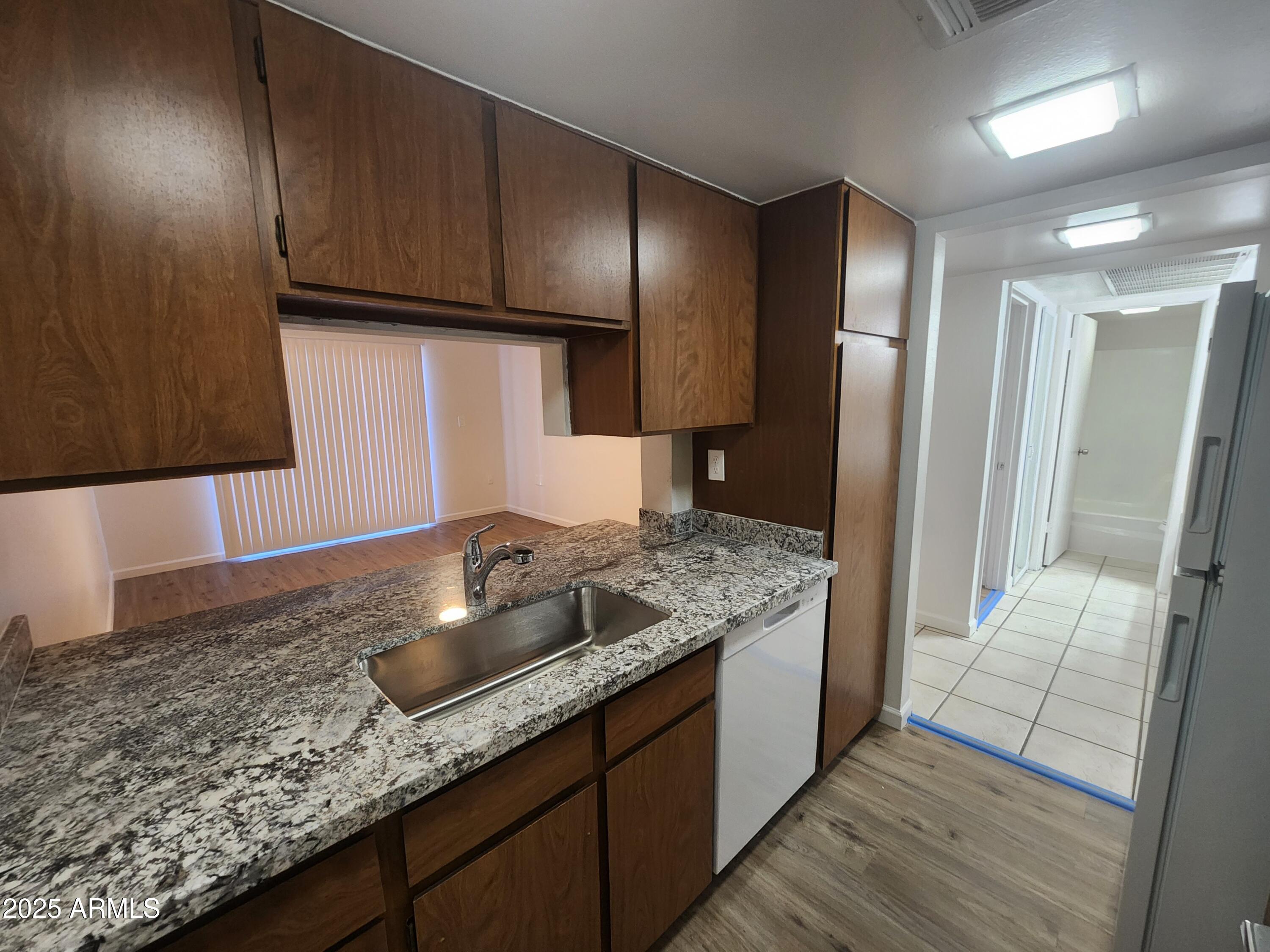 3033 East Devonshire Avenue, Unit 1028 Phoenix, AZ 85016 - Photo 3 of 27 a kitchen with granite countertop wooden cabinets and a stainless steel appliances