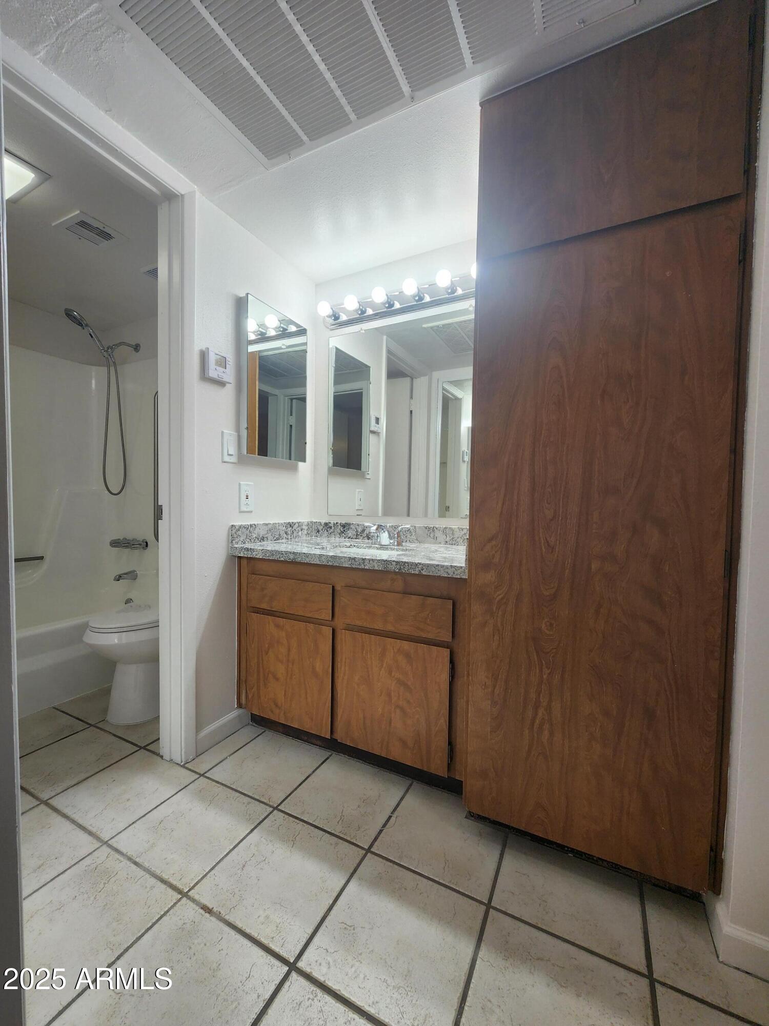 3033 East Devonshire Avenue, Unit 1028 Phoenix, AZ 85016 - Photo 9 of 27 a bathroom with a granite countertop sink a toilet and a mirror