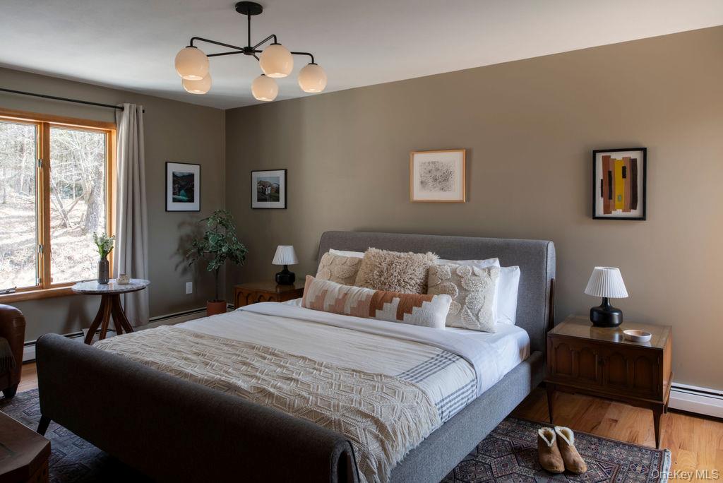 42 Lake Pleasant Road Staatsburg, NY 12580 - Photo 17 of 34 Bedroom with a baseboard radiator, multiple windows, a notable chandelier, and wood finished floors