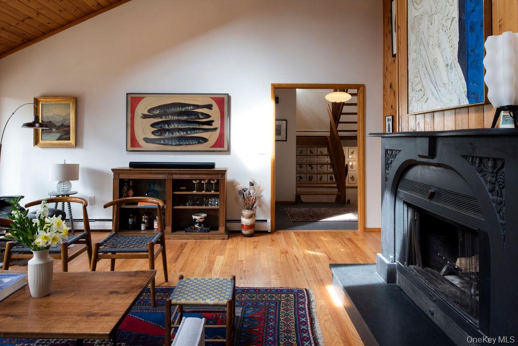 42 Lake Pleasant Road Staatsburg, NY 12580 - Photo 4 of 34 Living area featuring a wood-burning fireplace, wood floors, vaulted ceiling, and designer furniture