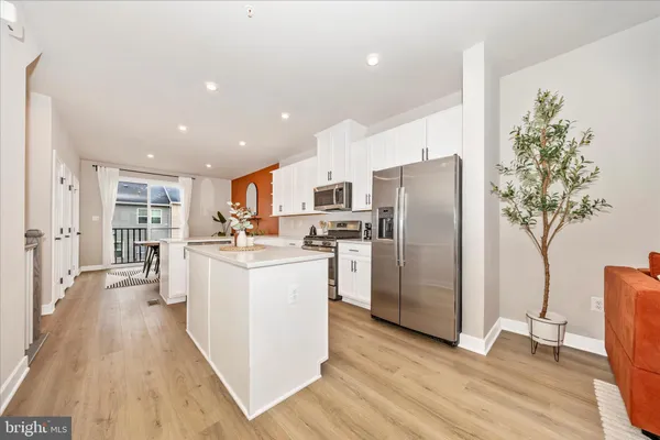 a kitchen with stainless steel appliances a refrigerator a stove a sink cabinets and wooden floor