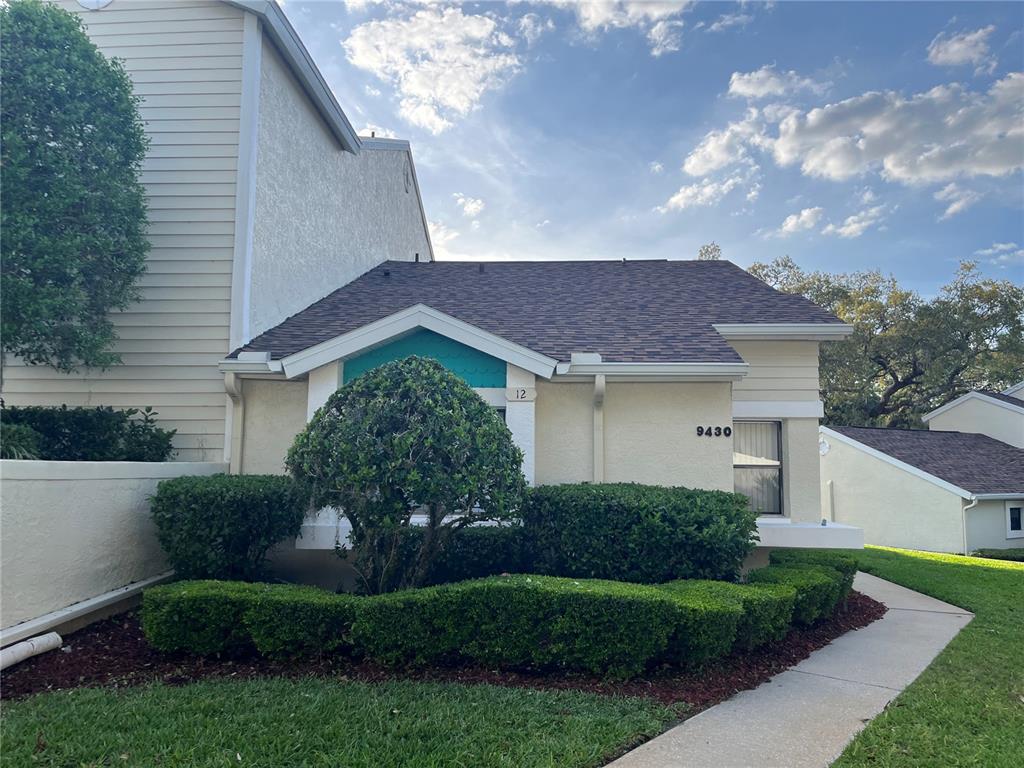 9430 Nakoma Way, Unit 12 Weeki Wachee, FL 34613 - Photo 1 of 20 a view of a house with a yard and a garden