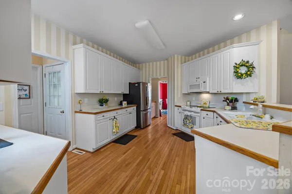 a kitchen that has a lot of cabinets in it wooden floor and appliances
