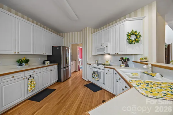 a large kitchen with stainless steel appliances granite countertop a lot of counter space and wooden floors