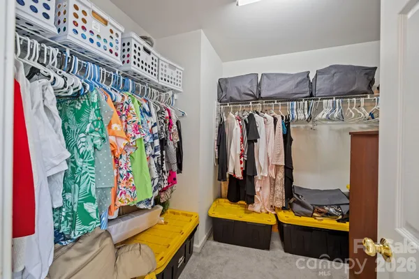 a view of walk in closet with clothes and shoes