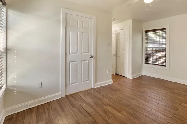 an empty room with wooden floor and windows