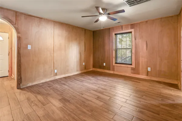 a view of an empty room with a window and wooden floor