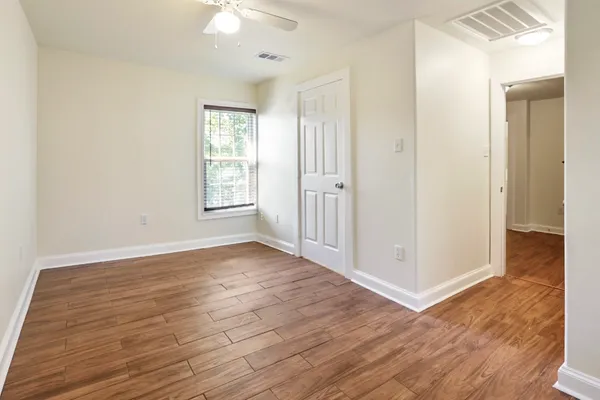an empty room with wooden floor and windows