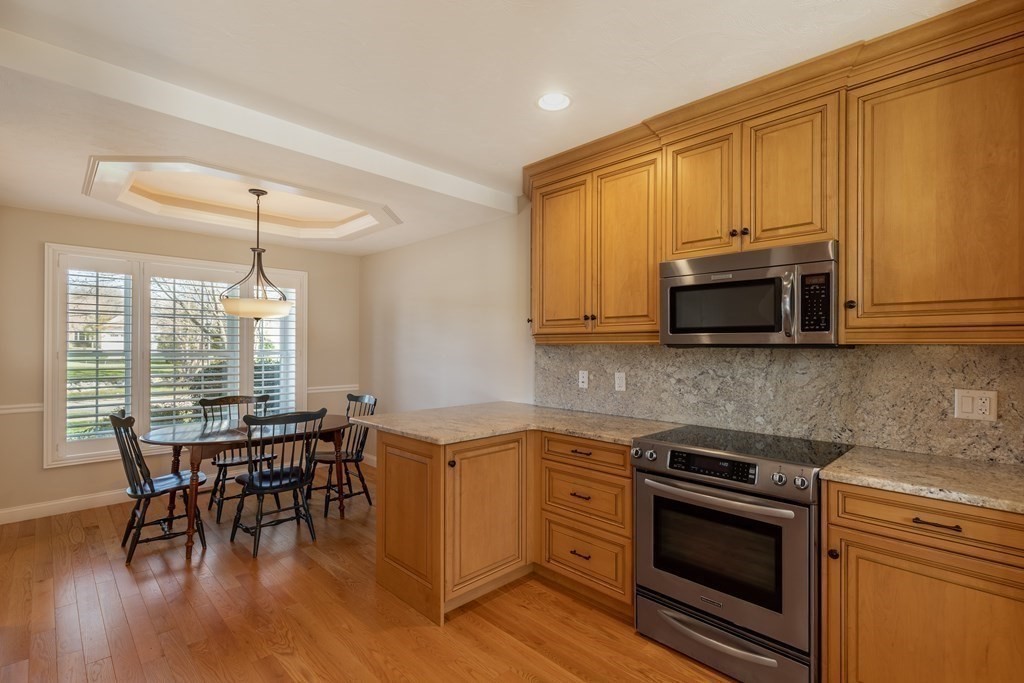22 English Commons: 12 Boston Street, Unit 22 Topsfield, MA 01983 - Photo 11 of 41 a kitchen with stainless steel appliances a stove a sink and white cabinets
