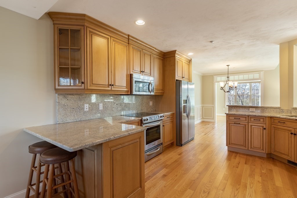 22 English Commons: 12 Boston Street, Unit 22 Topsfield, MA 01983 - Photo 13 of 41 a kitchen with stainless steel appliances granite countertop a kitchen island hardwood floor sink and stove