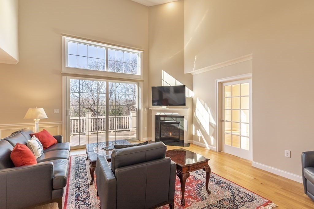 22 English Commons: 12 Boston Street, Unit 22 Topsfield, MA 01983 - Photo 9 of 41 a living room with furniture a flat screen tv and a floor to ceiling window