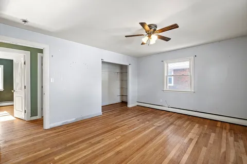 a view of an empty room with window and wooden floor
