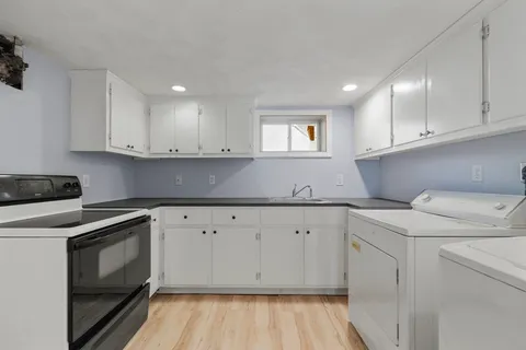 a kitchen with granite countertop white cabinets stainless steel appliances a sink and wooden floor