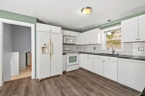 a kitchen with granite countertop a white refrigerator oven a sink and dishwasher with wooden floor