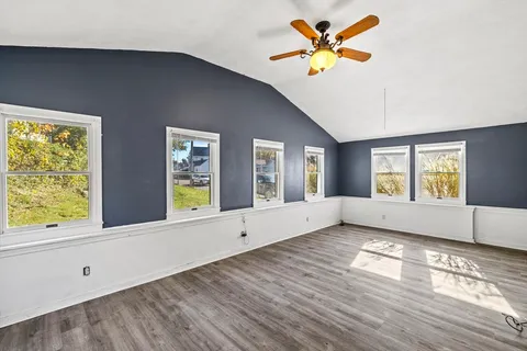a view of an empty room with window and wooden floor