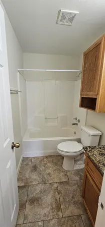 a bathroom with a granite countertop bathtub shower sink and toilet