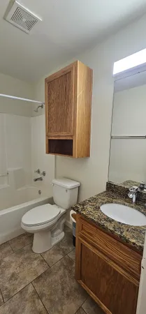a bathroom with a granite countertop toilet sink and mirror