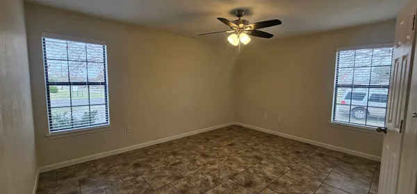 an empty room with windows and fan