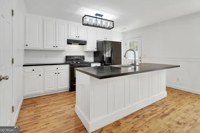 a kitchen with granite countertop a stove a sink and a white cabinets