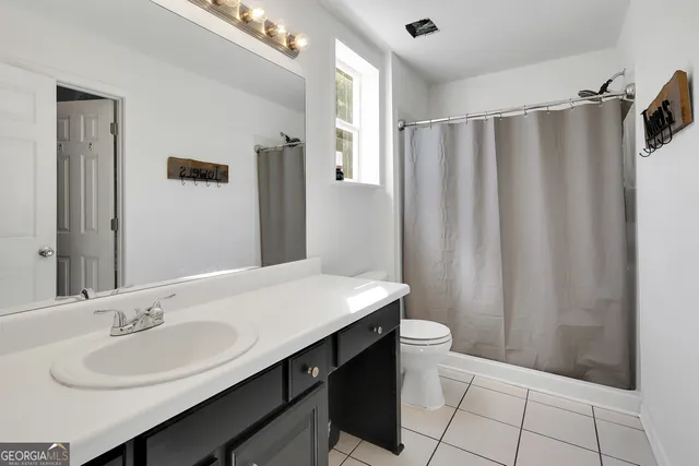 a bathroom with a sink a toilet a mirror and shower curtain