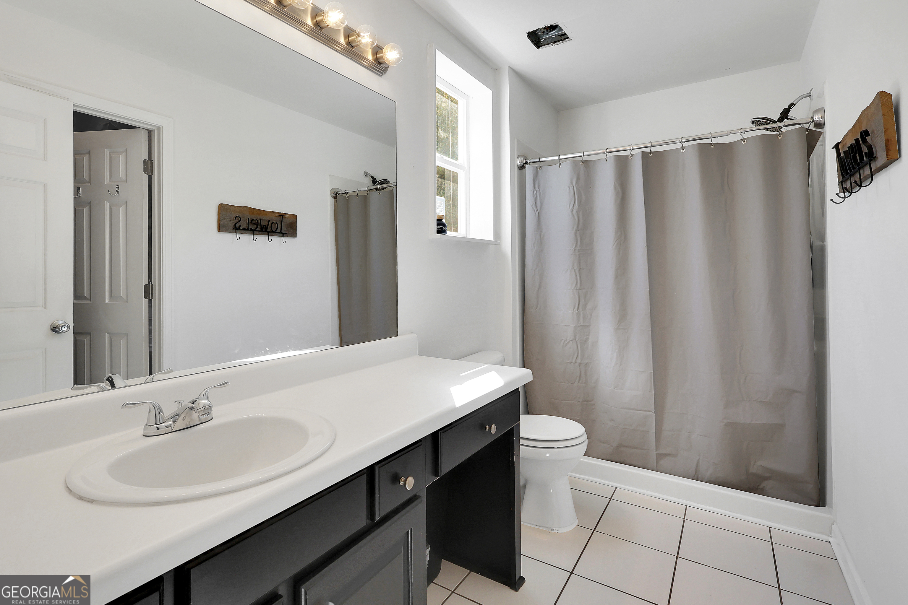 394 Burg Road Locust Grove, GA 30248 - Photo 25 of 40 a bathroom with a sink a toilet a mirror and shower curtain