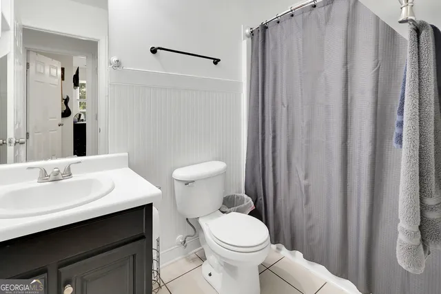 a bathroom with a sink a toilet a mirror and shower curtain