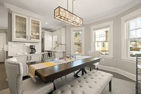 a dining room with wooden floor and large windows
