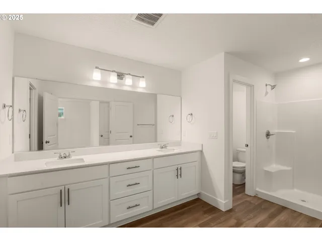 a bathroom with a double vanity sink and mirror with shower