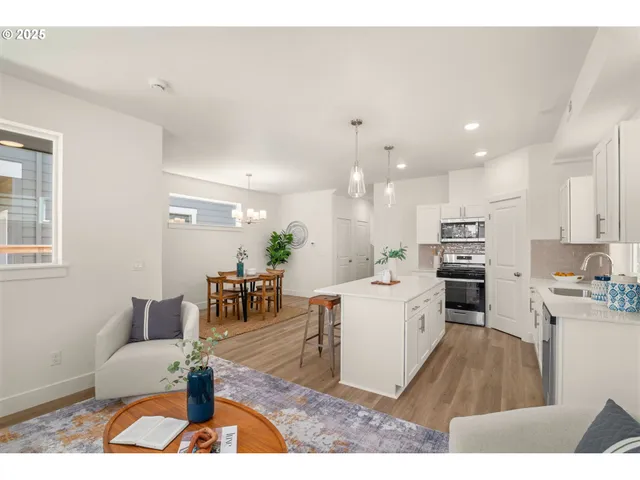 a living room with stainless steel appliances kitchen island granite countertop furniture and a wooden floor