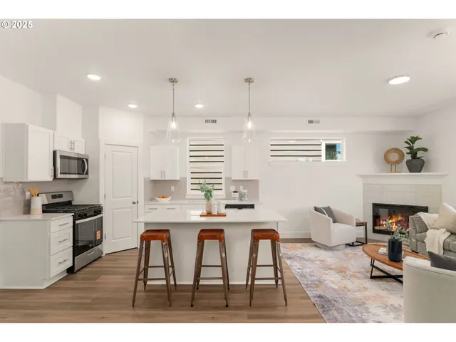 a living room with stainless steel appliances kitchen island granite countertop furniture a fireplace a rug and a window