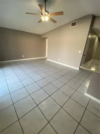 a view of an empty room and chandelier fan