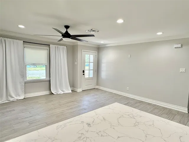 an empty room with wooden floor and windows
