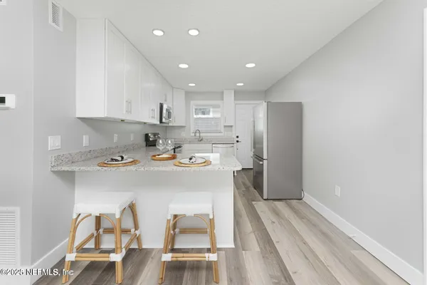 a kitchen with stainless steel appliances granite countertop a stove a refrigerator and a sink with wooden floor