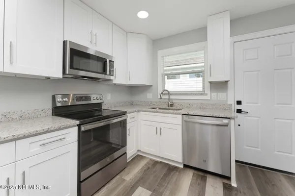 a kitchen with stainless steel appliances granite countertop white cabinets granite counter tops and a window