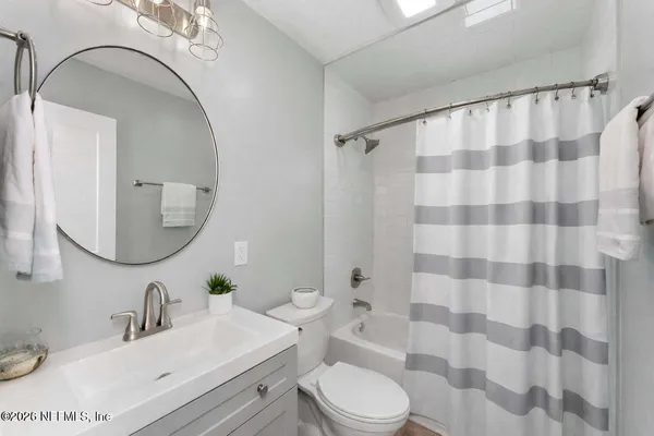 a bathroom with a sink a toilet a mirror and shower curtain