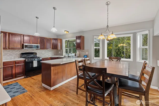 a kitchen with stainless steel appliances granite countertop a stove a refrigerator a kitchen island a dining table and chairs