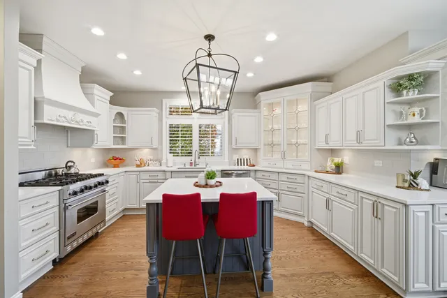 a kitchen with stainless steel appliances a dining table chairs stove and white cabinets