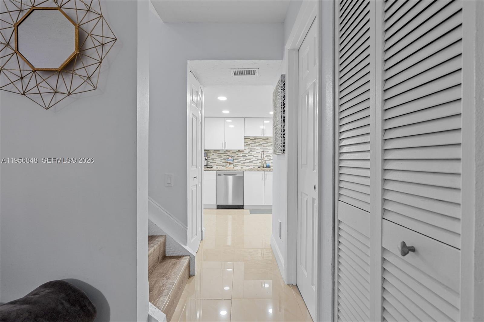 6554 Southwest 114th Place, Unit E74 Miami, FL 33173 - Photo 19 of 51 Hall between living room and kitchen, you can see the AC closet door and the half bath door across the staircase.