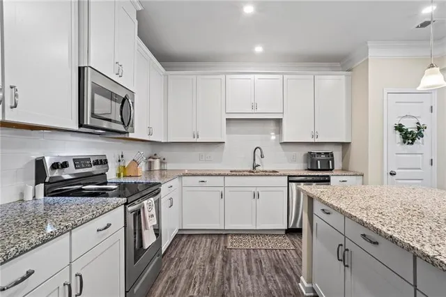 a kitchen with granite countertop cabinets stainless steel appliances a sink and wooden floor