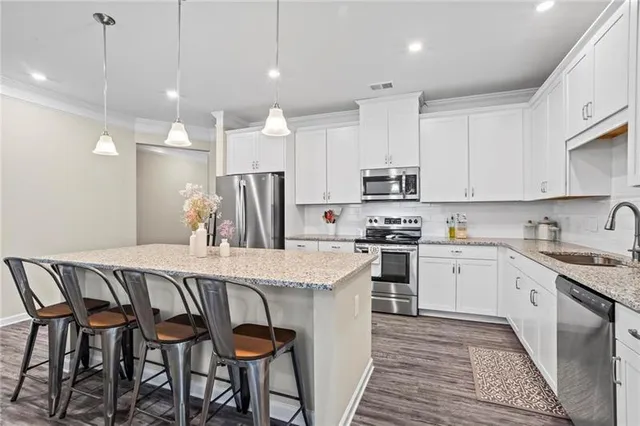 a kitchen with granite countertop a sink stainless steel appliances and white cabinets