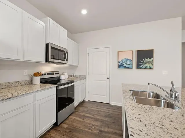 a kitchen with stainless steel appliances granite countertop a stove a sink and a microwave