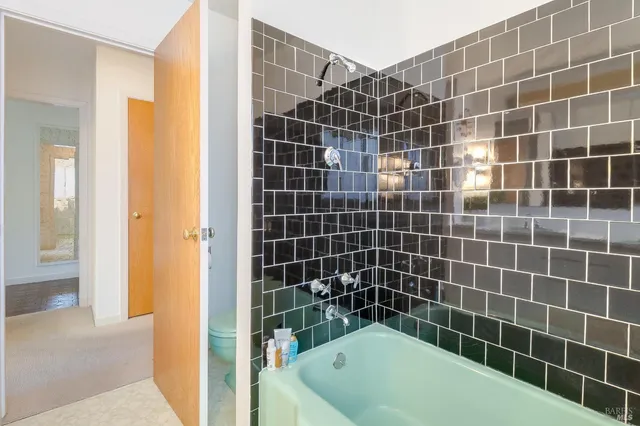 a bathroom with a granite countertop sink a toilet and shower curtain