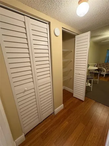 a view of a hallway with wooden floor and closet