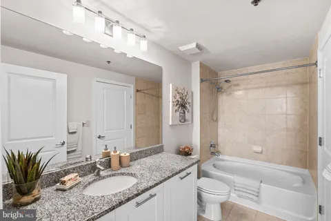 a bathroom with a granite countertop sink a mirror a toilet and a bathtub