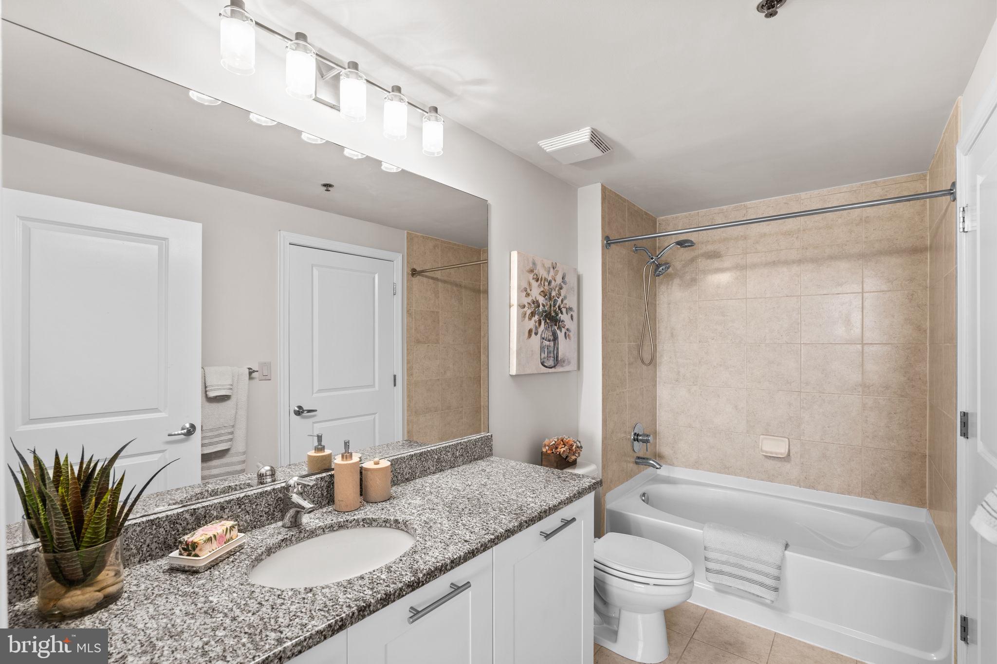 5750 Bou Avenue, Unit 1106 North Bethesda, MD 20852 - Photo 12 of 54 a bathroom with a granite countertop sink a mirror a toilet and a bathtub