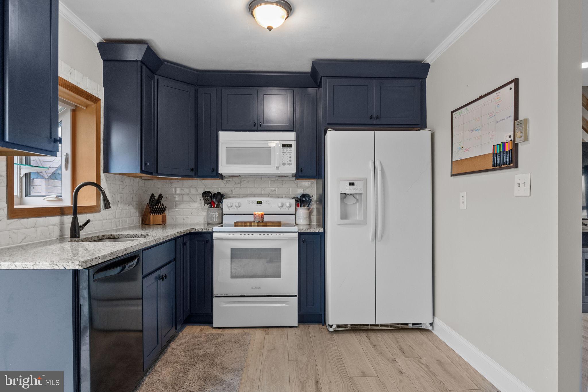 19 Violet Road Levittown, PA 19057 - Photo 7 of 26 a kitchen with granite countertop a refrigerator stove and sink with wooden floor