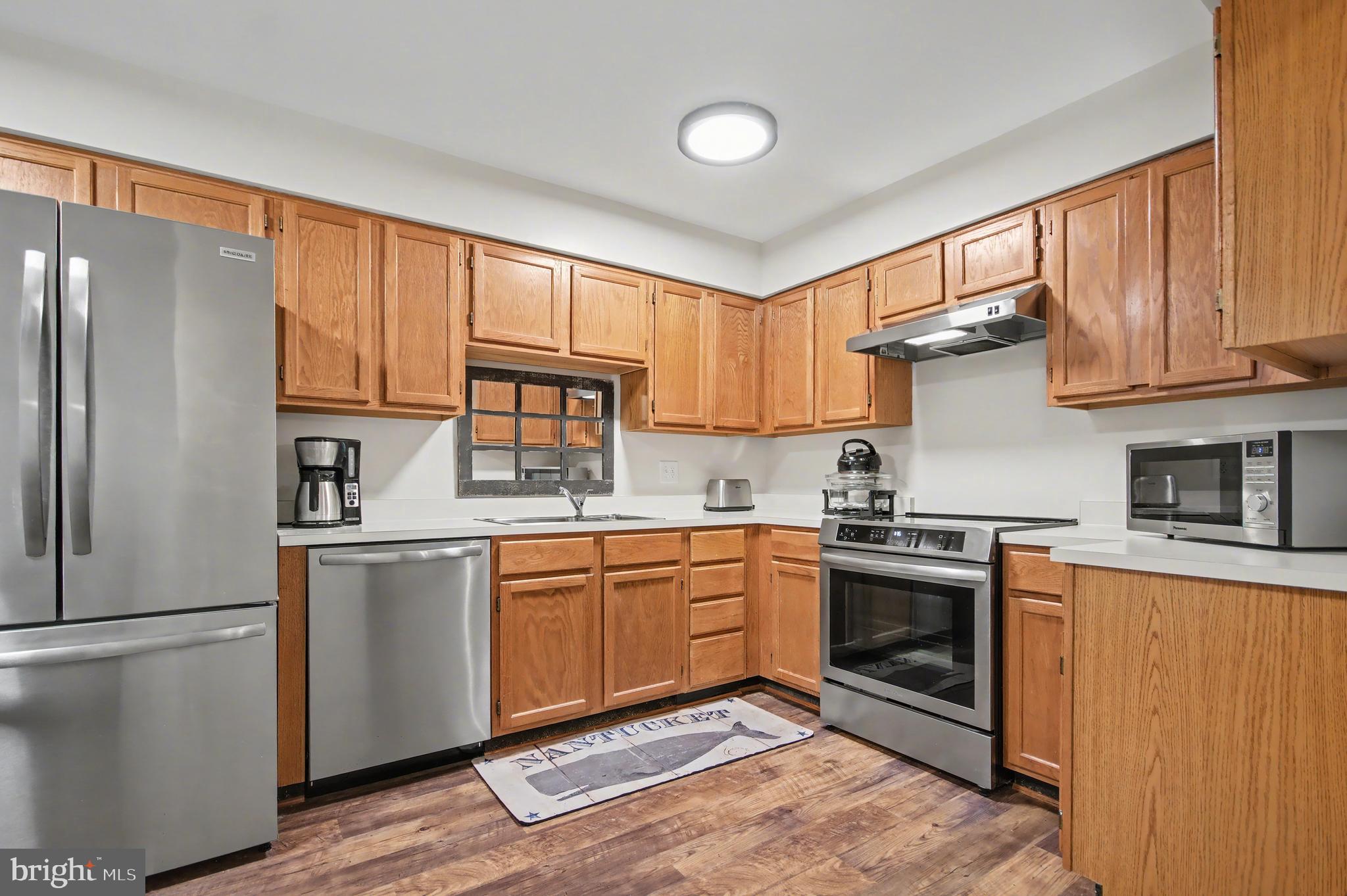 2900 Shipmaster Way, Unit 312 Annapolis, MD 21401 - Photo 6 of 56 a kitchen with stainless steel appliances granite countertop a refrigerator a sink dishwasher a stove and white countertops with wooden floor